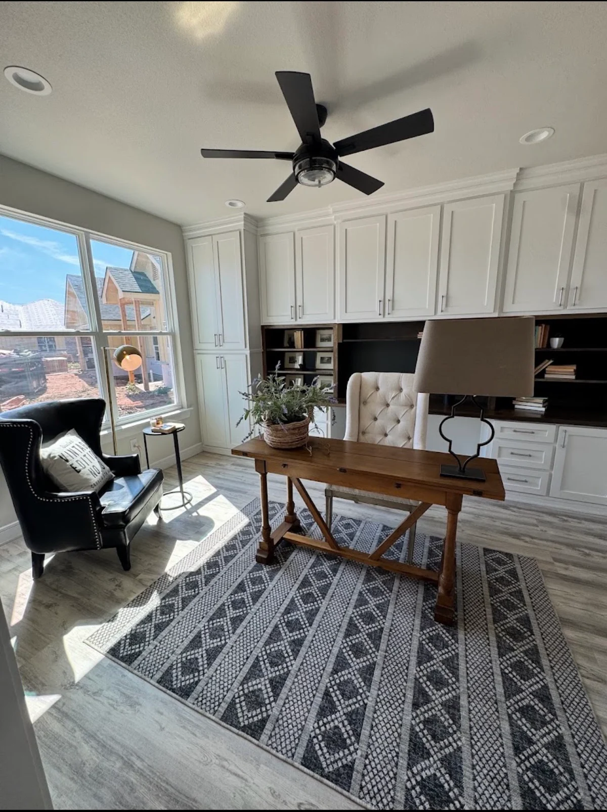 White built-in office cabinets with dark open shelves behind a wooden desk